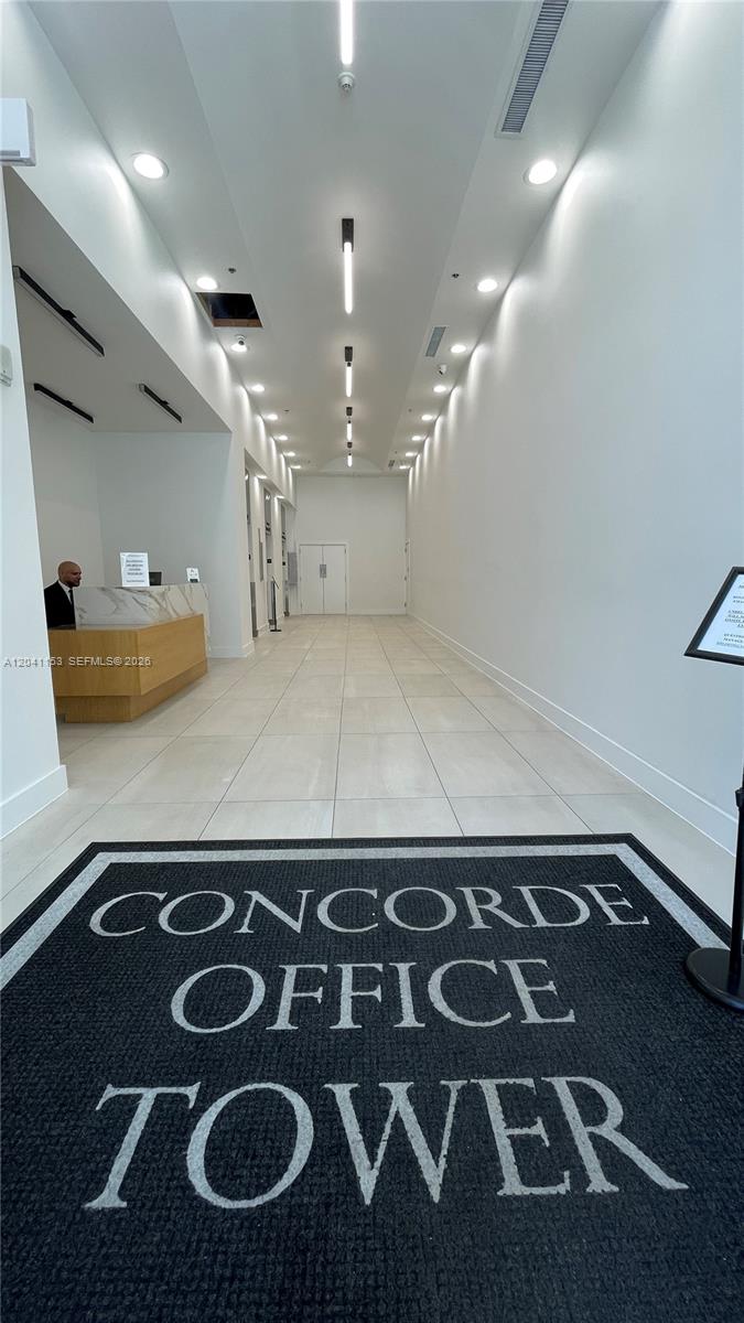 A modern office building lobby features a reception desk, tiled floors, and recessed lighting — 66 W Flagler St # 320, Miami FL 33130, MIAMI, FL