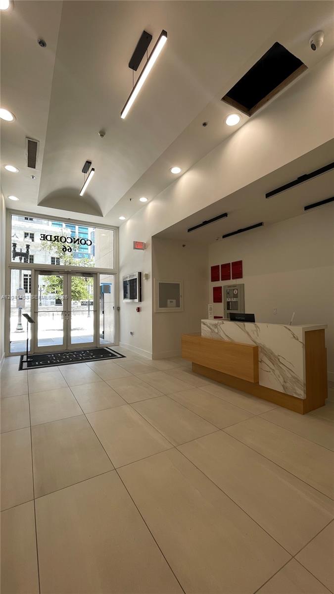 A modern office building lobby features a marble reception desk and large glass entrance doors — 66 W Flagler St # 320, Miami FL 33130, MIAMI, FL