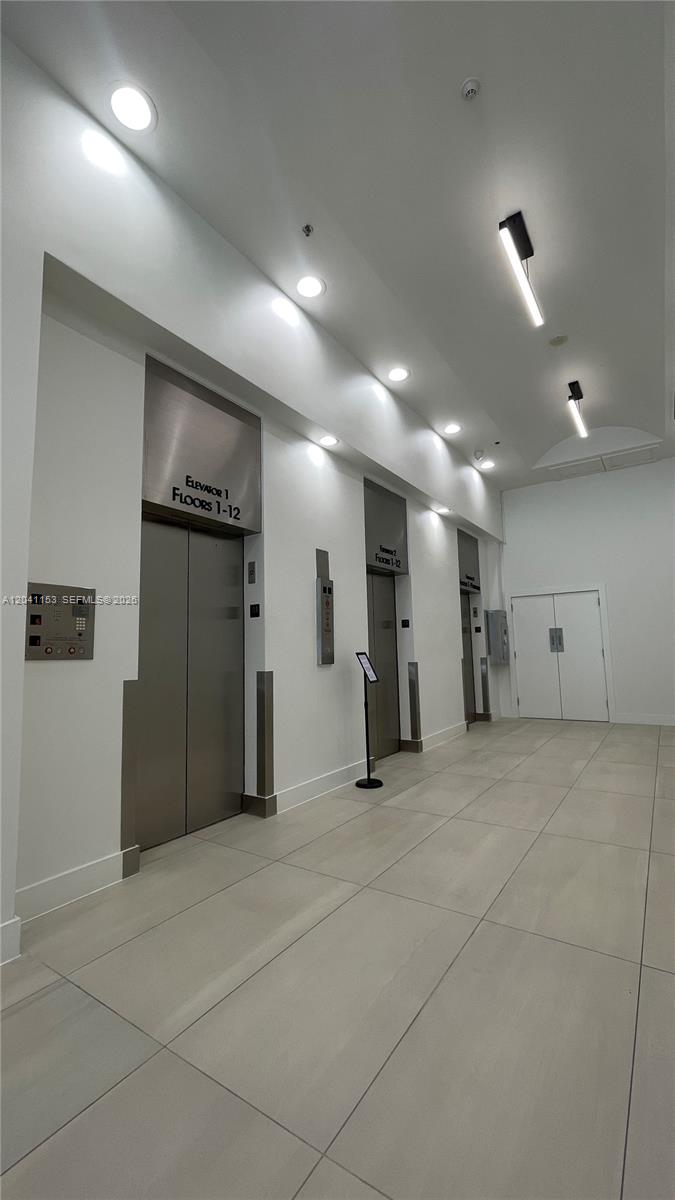 A modern building lobby features two stainless steel elevators and white tile flooring — 66 W Flagler St # 320, Miami FL 33130, MIAMI, FL