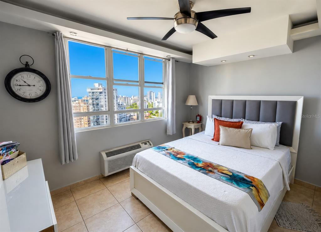 A bedroom features a queen bed, a ceiling fan, and large windows with city views — 602 Ave Fernandez Juncos COND. SEA VIEW UNIT 1704, SAN JUAN, PR