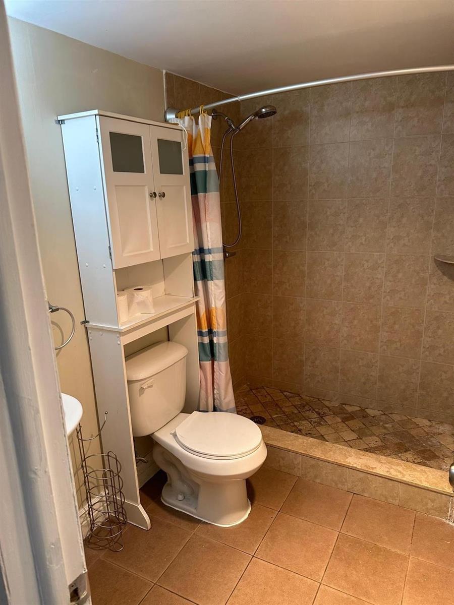 A bathroom features a toilet with an over-the-toilet storage unit and a tiled walk-in shower — 400 N Riverside Drive # 102, Pompano Beach FL 33062, POMPANO BEACH, FL
