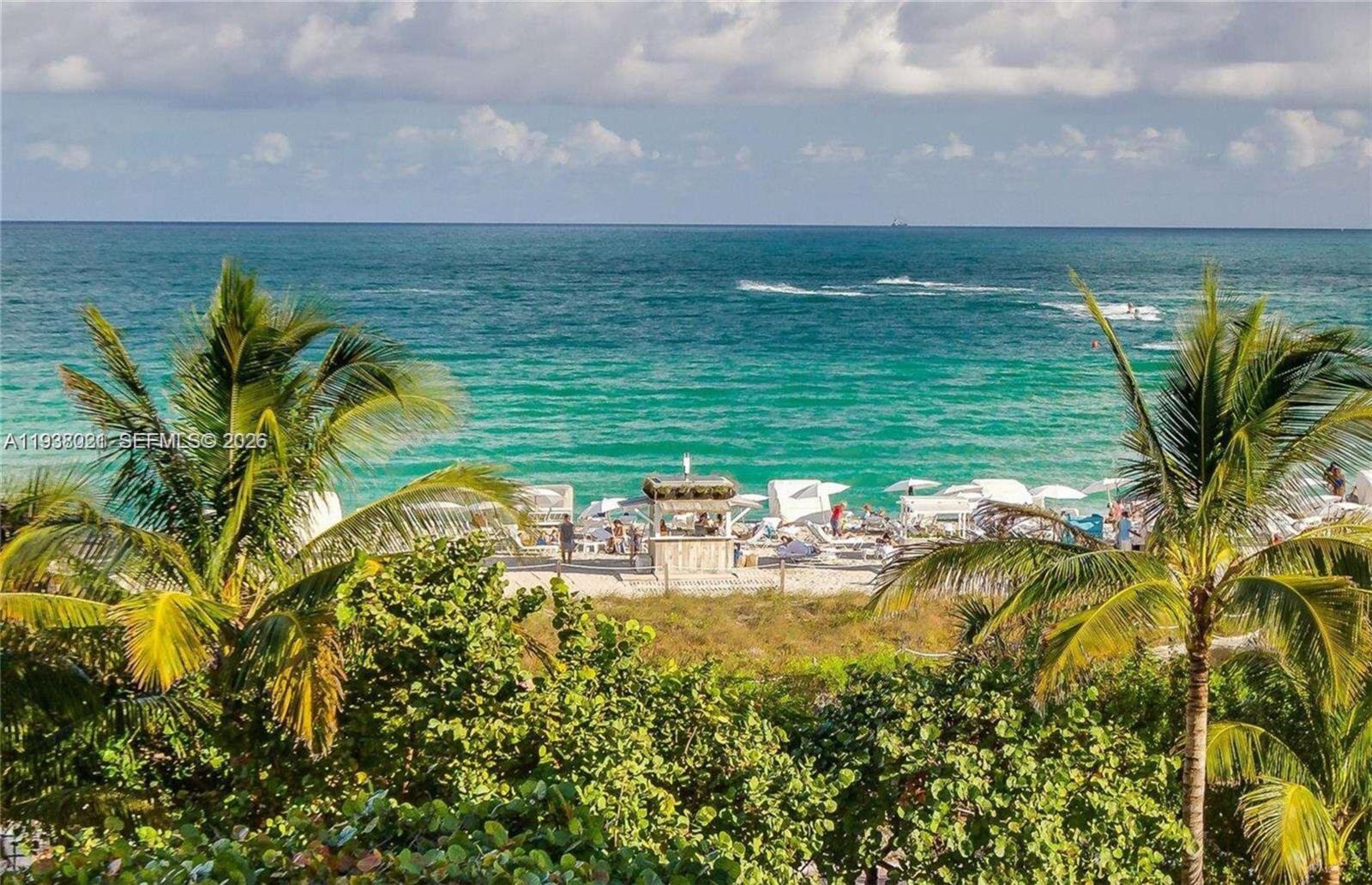 A view of a sandy beach with a small wooden hut and palm trees — 2301 Collins Ave # 423, Miami Beach FL 33139, MIAMI BEACH, FL