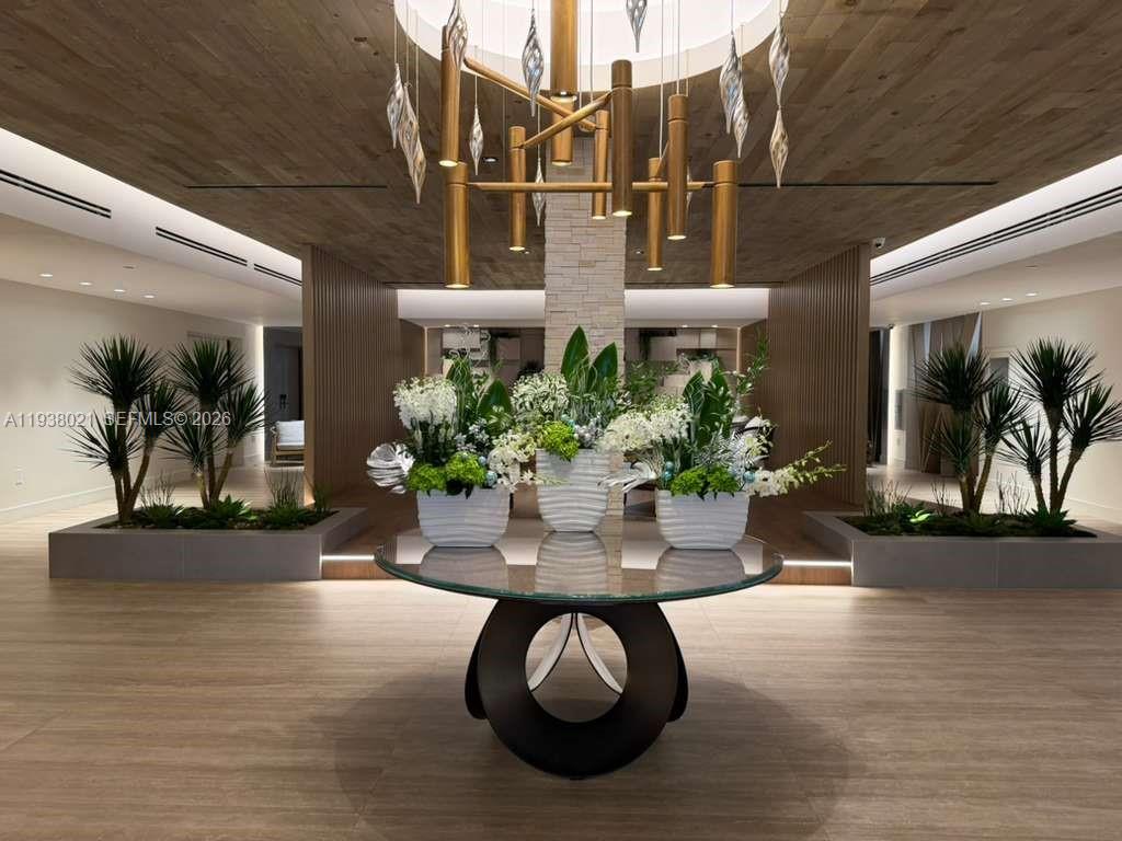 A modern lobby features a glass-topped table, floral arrangements, and a sculptural gold chandelier — 2301 Collins Ave # 423, Miami Beach FL 33139, MIAMI BEACH, FL