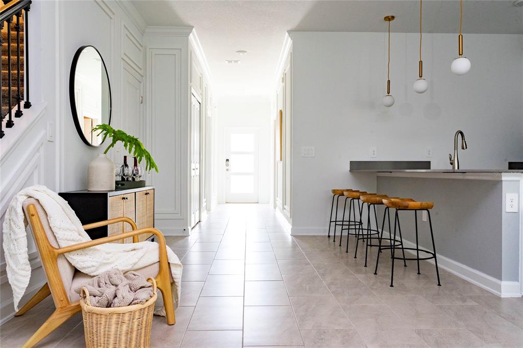 A bright entryway features a chair, a console table, and a kitchen island with barstools — 4355 SCENE LANE, KISSIMMEE, FL