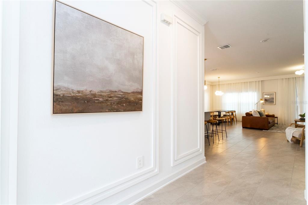 A hallway with white wainscoting leads into an open-concept living area with tile flooring — 4355 SCENE LANE, KISSIMMEE, FL