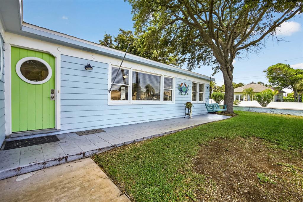 A light blue house with a bright green door and a tiled patio area — 731 N OLEANDER AVENUE, DAYTONA BEACH, FL