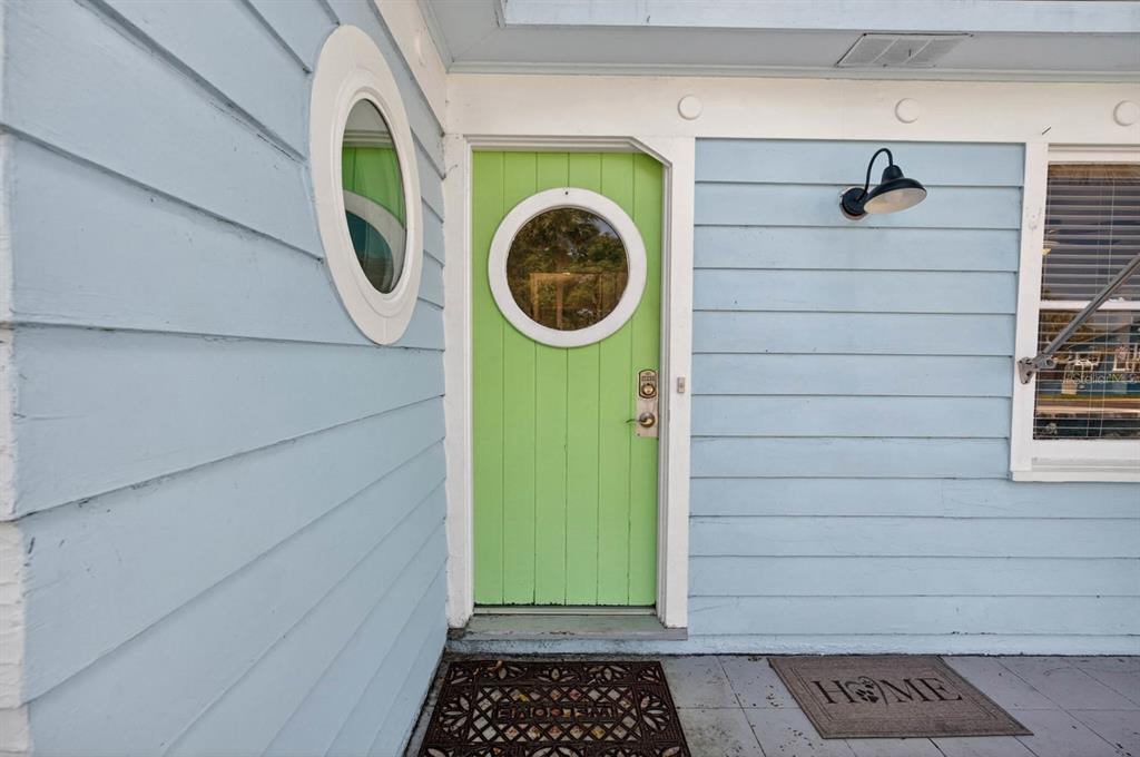 A light green door with a circular window sits on a light blue exterior wall — 731 N OLEANDER AVENUE, DAYTONA BEACH, FL