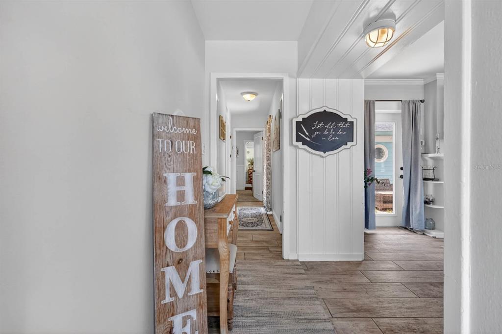 A hallway with light wood-look tile flooring leads to a doorway and an adjacent room — 731 N OLEANDER AVENUE, DAYTONA BEACH, FL