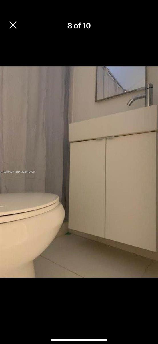 A bathroom featuring a white vanity cabinet, a sink, and a portion of a toilet — 126 Mendoza Ave # 1, Coral Gables FL 33134, CORAL GABLES, FL