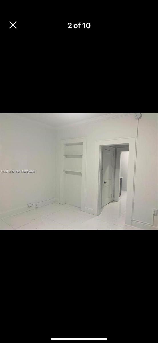 A white room features tiled floors, built-in wall shelving, and a doorway leading to another room — 126 Mendoza Ave # 1, Coral Gables FL 33134, CORAL GABLES, FL
