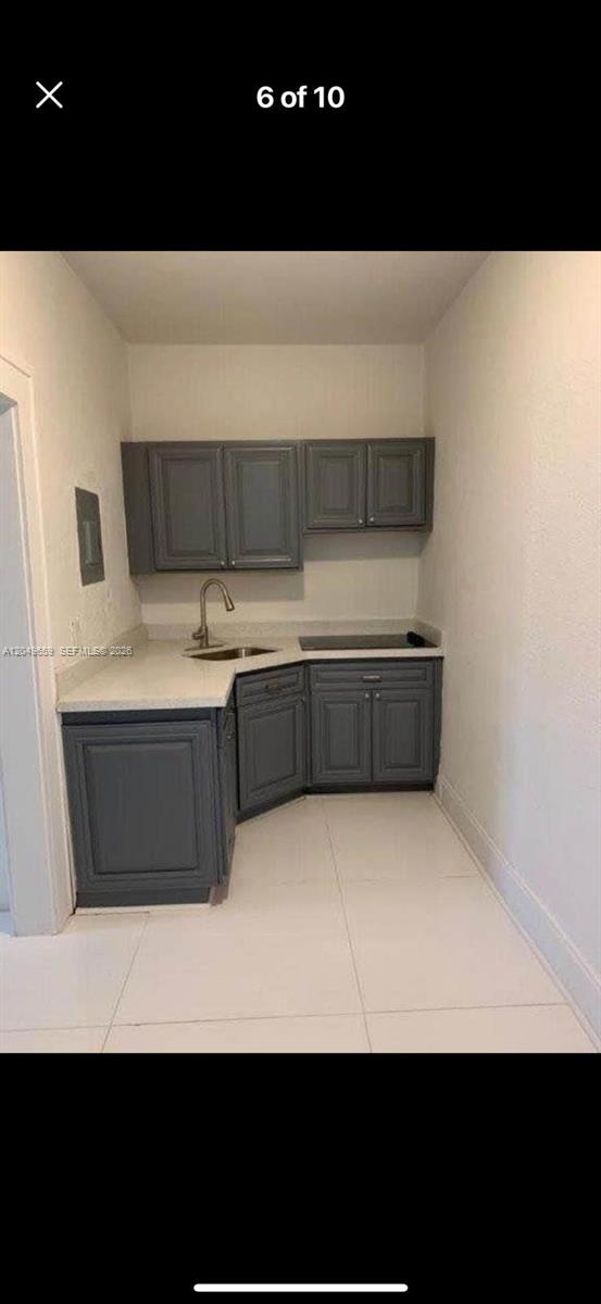 A small kitchenette features gray cabinets, white countertops, a sink, and a cooktop — 126 Mendoza Ave # 1, Coral Gables FL 33134, CORAL GABLES, FL