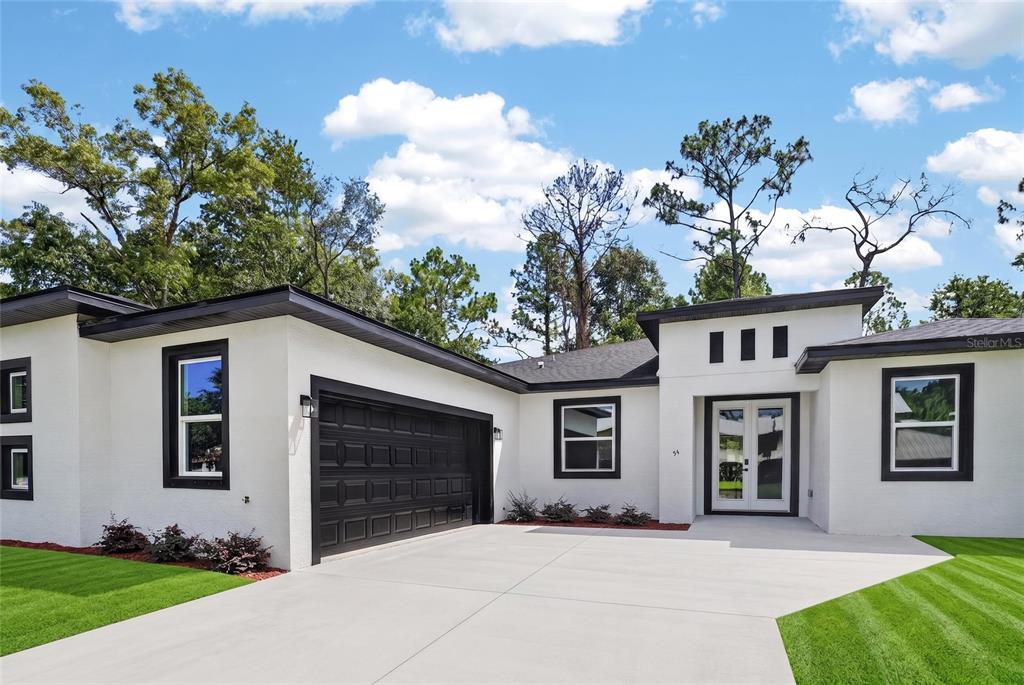 A white single-story house with a black garage door and black window trim — 54 DOUGLAS STREET, HOMOSASSA, FL