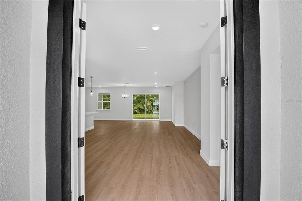 A view through an open doorway into an empty living area with wood-look flooring — 54 DOUGLAS STREET, HOMOSASSA, FL
