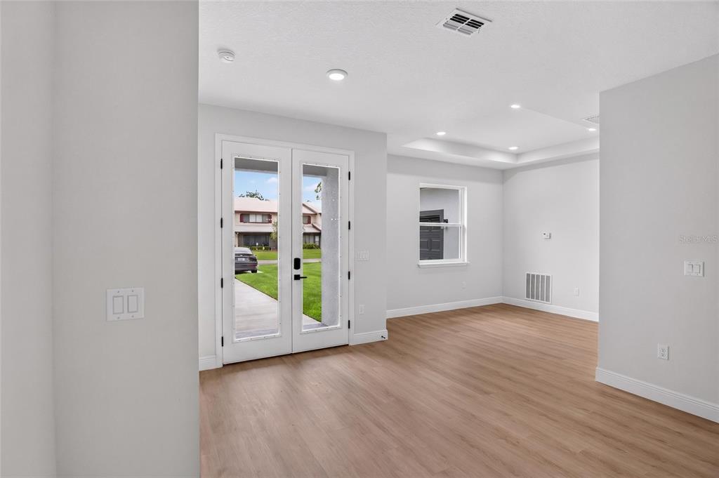 An interior view of a room with light wood flooring, white walls, and double glass doors — 54 DOUGLAS STREET, HOMOSASSA, FL