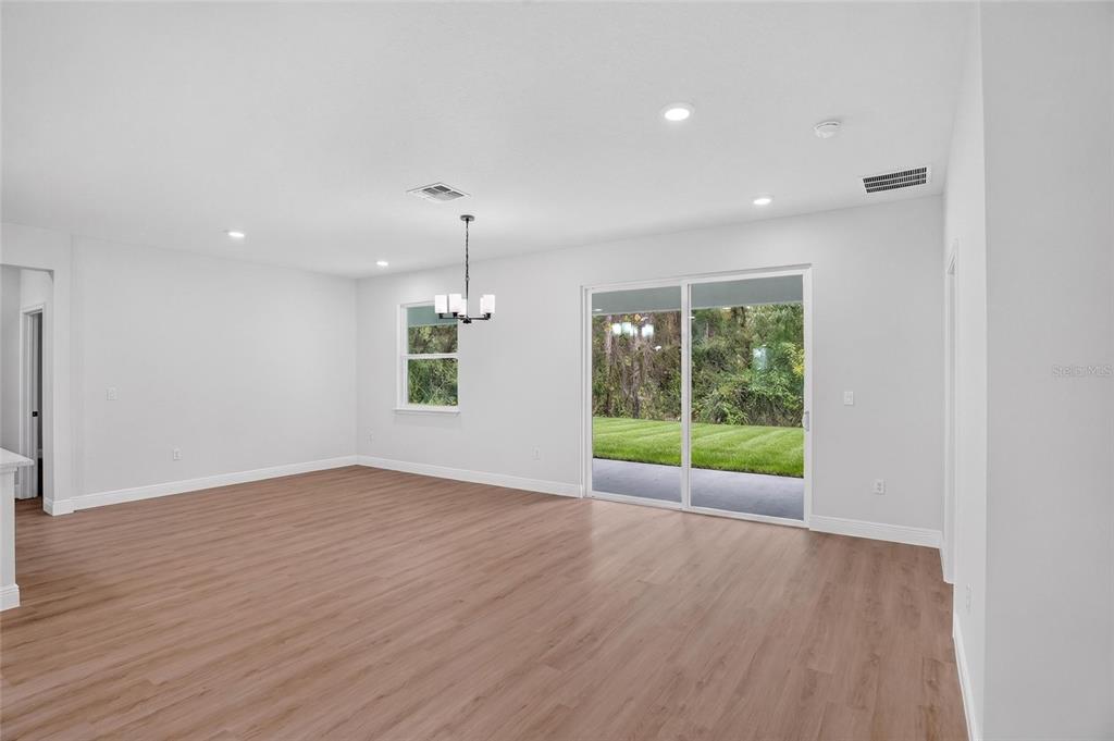 An empty room with light wood-look flooring, white walls, a chandelier, and sliding glass doors — 54 DOUGLAS STREET, HOMOSASSA, FL