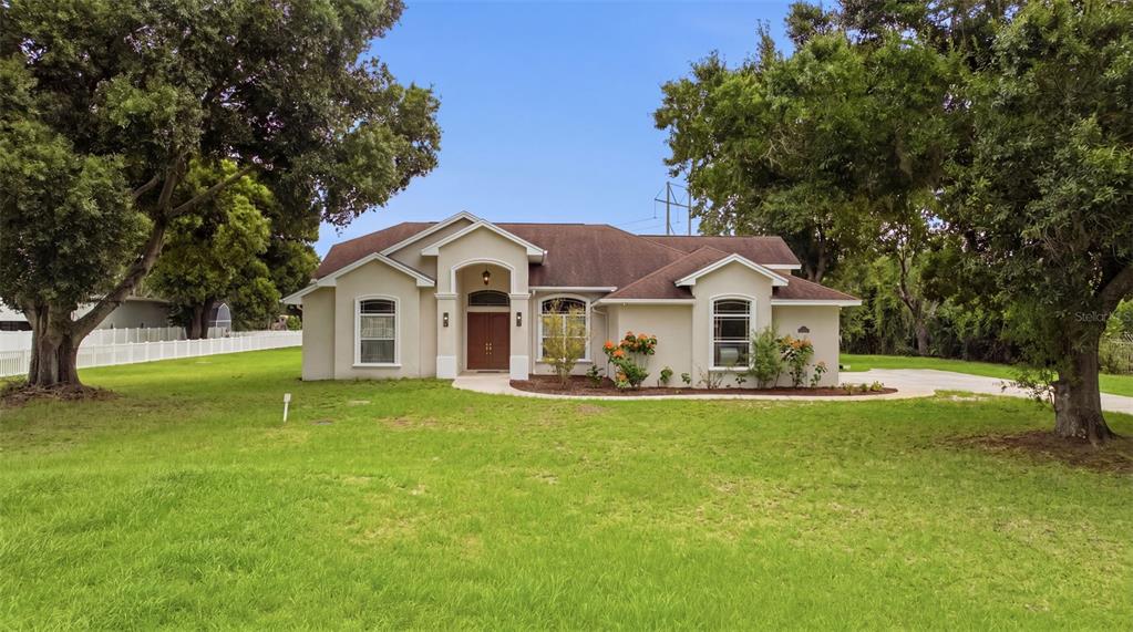 A single-story house with a beige stucco exterior and a brown shingled roof — 17127 BROWN ROAD, ODESSA, FL