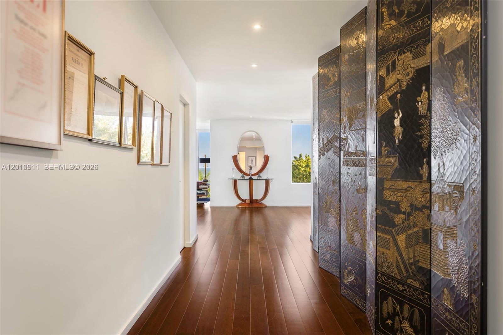 A hallway with dark wood floors, framed wall art, and a large decorative folding screen — 200 Ocean Lane Dr # 401, Key Biscayne FL 33149, KEY BISCAYNE, FL