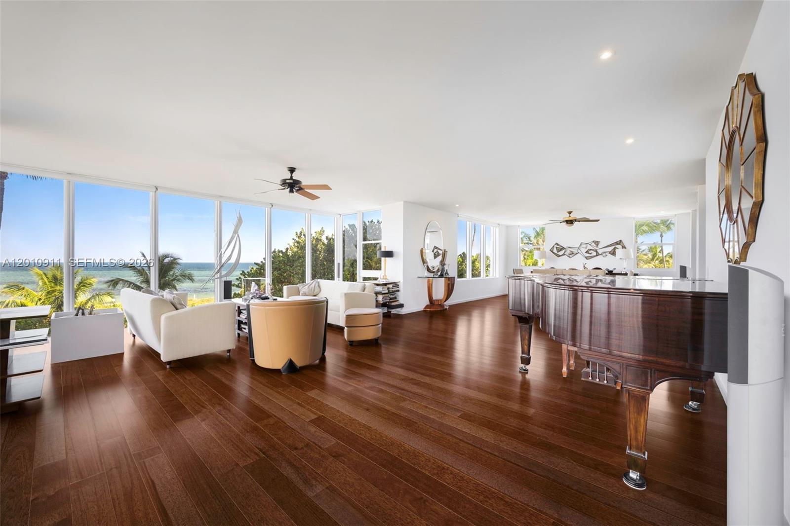 A spacious living room features dark hardwood floors, a grand piano, and floor-to-ceiling ocean views — 200 Ocean Lane Dr # 401, Key Biscayne FL 33149, KEY BISCAYNE, FL