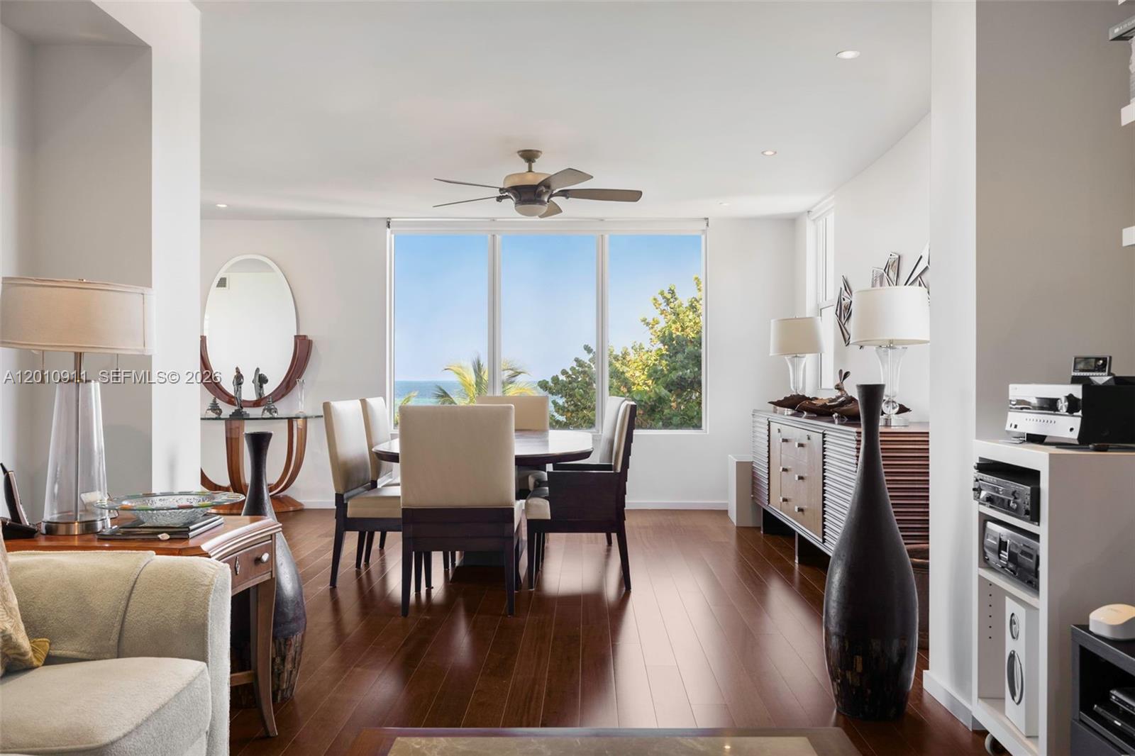 A dining room features dark wood floors, a central table, and large windows with ocean views — 200 Ocean Lane Dr # 401, Key Biscayne FL 33149, KEY BISCAYNE, FL