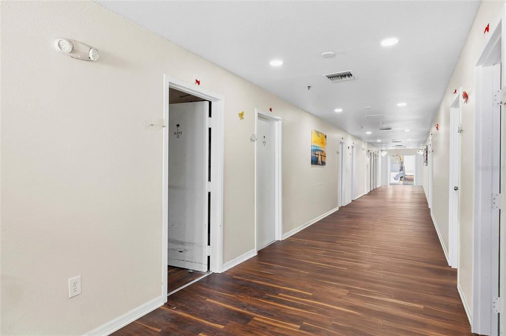 A long commercial hallway features wood-look flooring, white walls, and multiple doors leading to suites — 820 15TH STREET N, ST PETERSBURG, FL