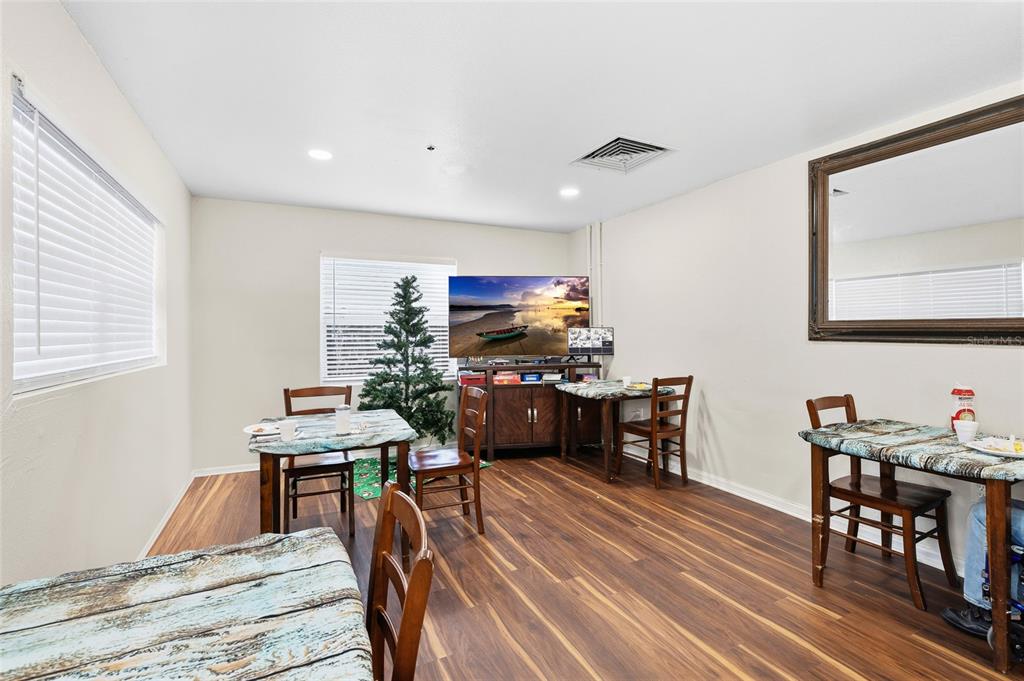 A dining room features wood-look flooring, multiple tables, a television, and a Christmas tree — 820 15TH STREET N, ST PETERSBURG, FL