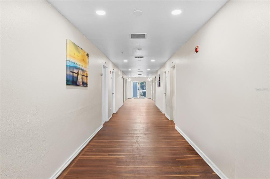 A long, brightly lit indoor hallway features wood-look flooring and white walls with doors — 820 15TH STREET N, ST PETERSBURG, FL