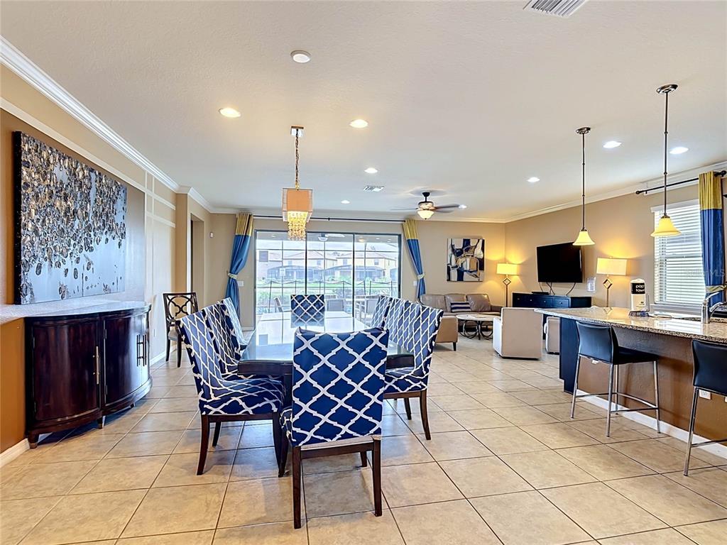 An open-concept dining and living area features tile flooring, blue patterned chairs, and pendant lighting — 1829 GOBI DRIVE, KISSIMMEE, FL