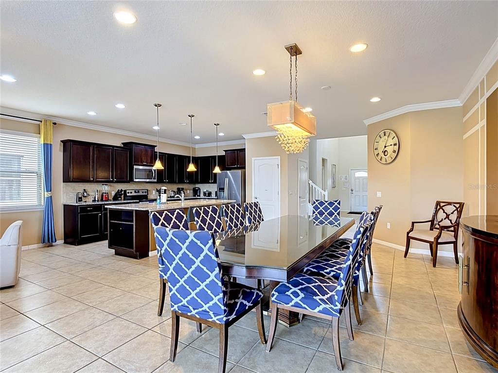 A dining area with a glass-topped table and patterned chairs sits beside an open kitchen — 1829 GOBI DRIVE, KISSIMMEE, FL