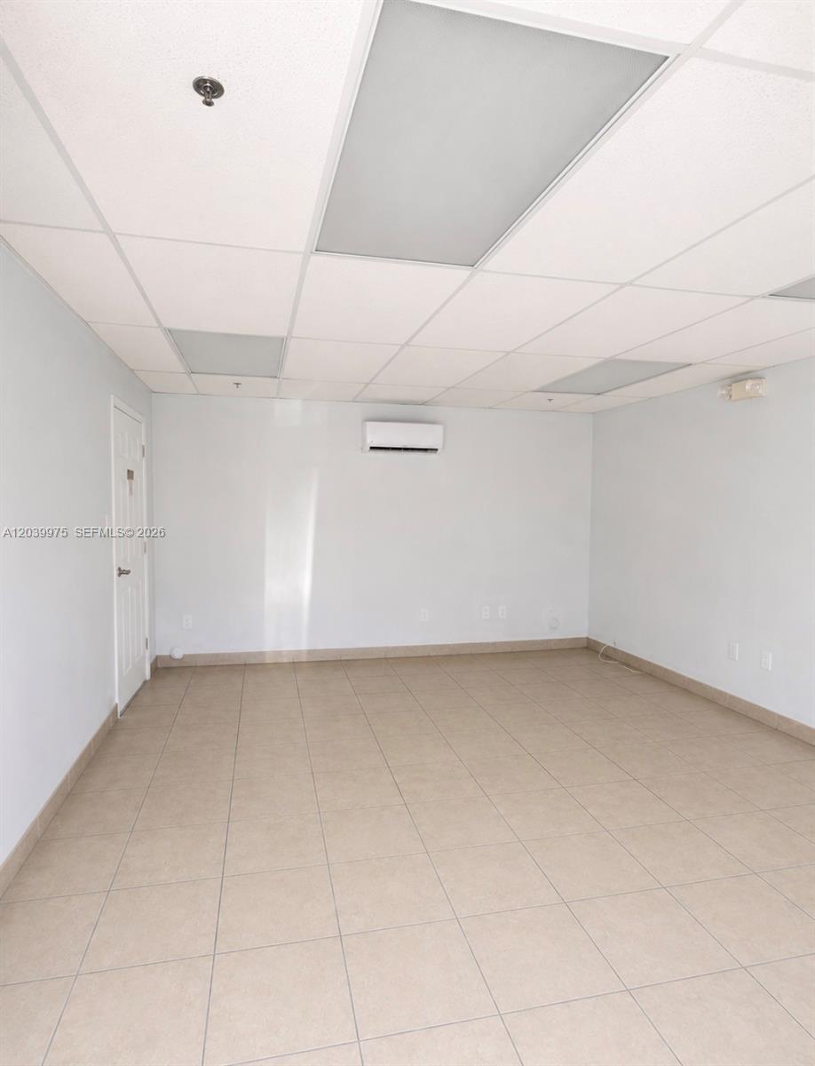 An empty room features white walls, a drop ceiling with recessed lighting, and tiled flooring — MIAMI, FL