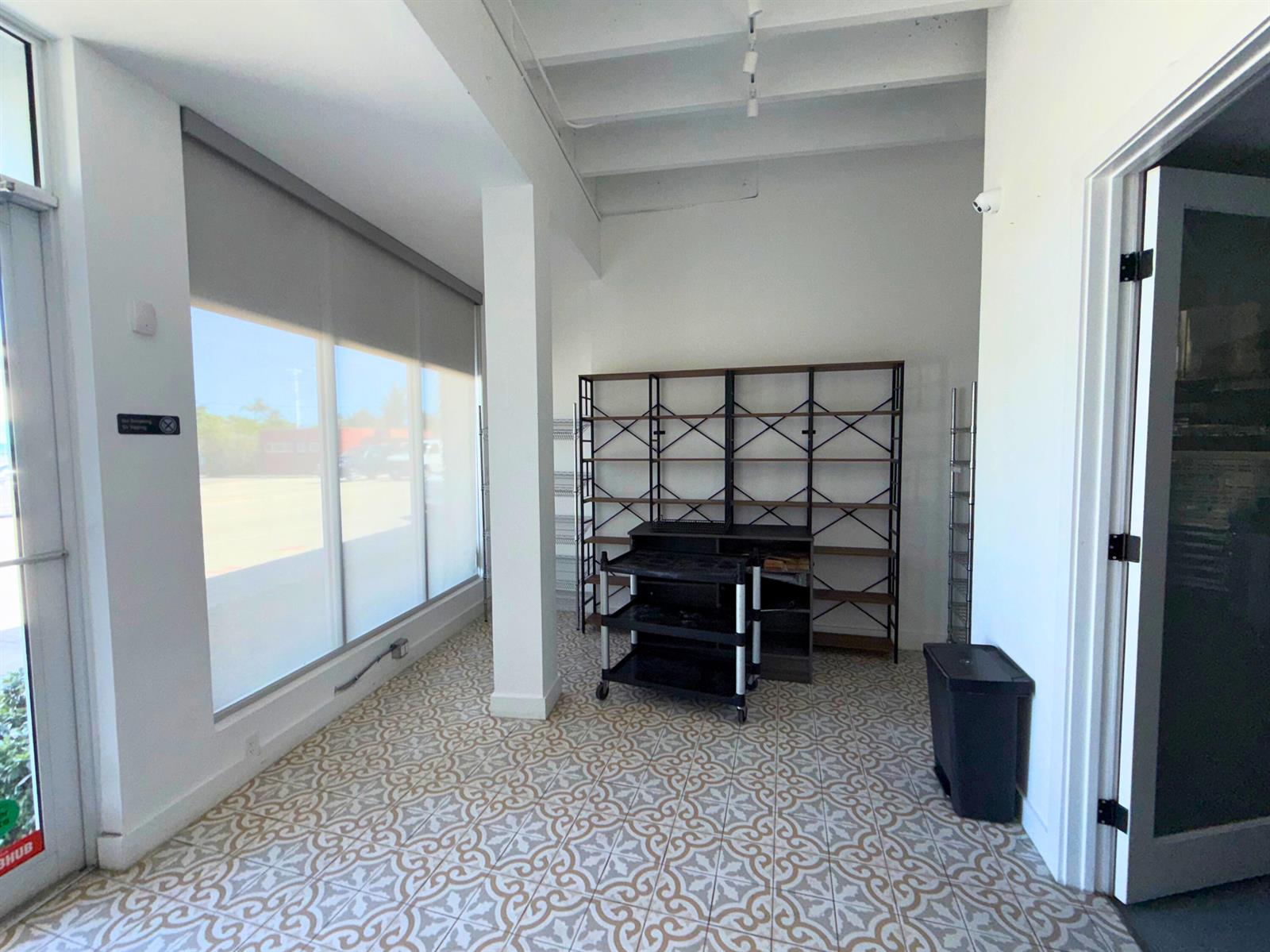A bright room features patterned tile flooring, large windows with shades, and metal shelving units — 5505 S Dixie Highway # 4, West Palm Beach FL 33405, WEST PALM BEACH, FL