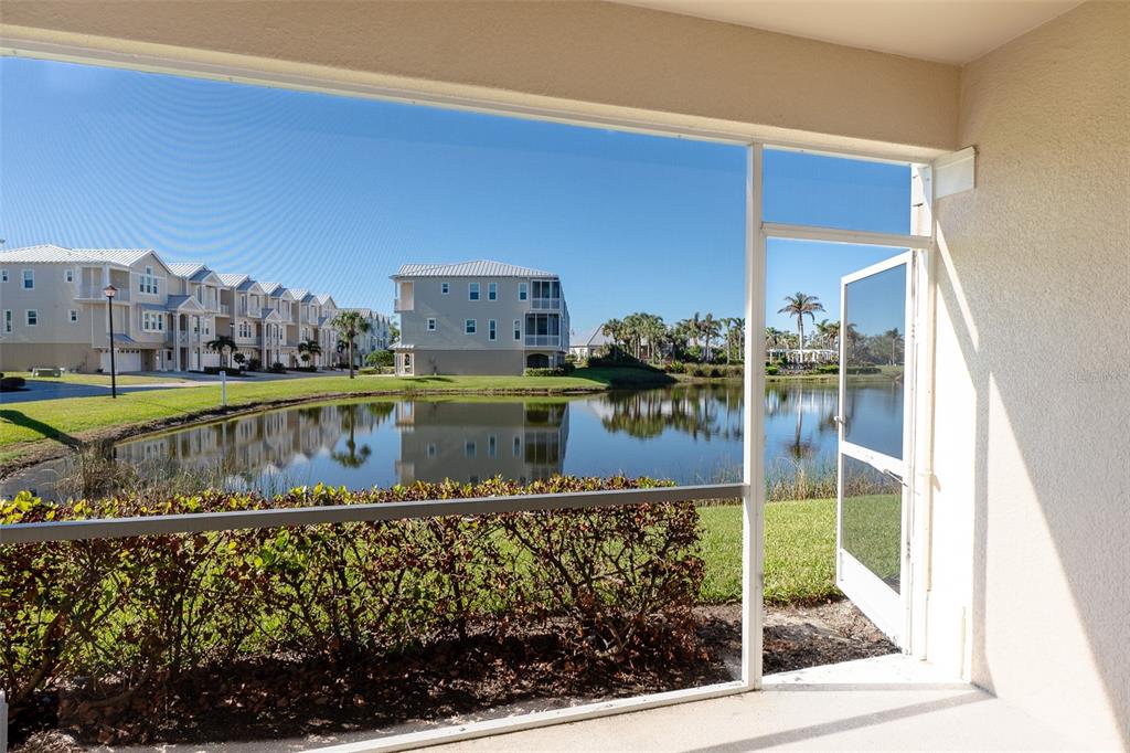 A screened-in porch overlooks a pond and residential buildings on a sunny day — 10345 LONGSHORE ROAD UNIT 31, PLACIDA, FL