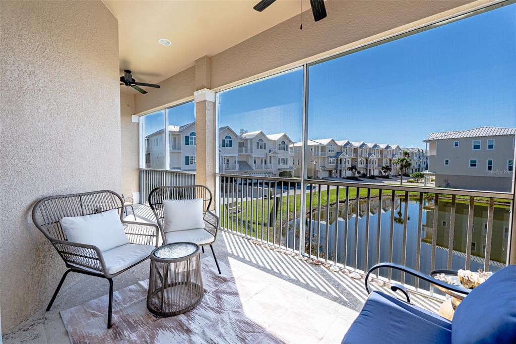 A screened-in balcony features outdoor furniture, a patterned rug, and views of a pond — 10345 LONGSHORE ROAD UNIT 31, PLACIDA, FL