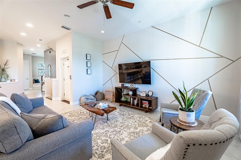 A living room features a geometric accent wall, a television, and gray upholstered furniture — 10345 LONGSHORE ROAD UNIT 31, PLACIDA, FL