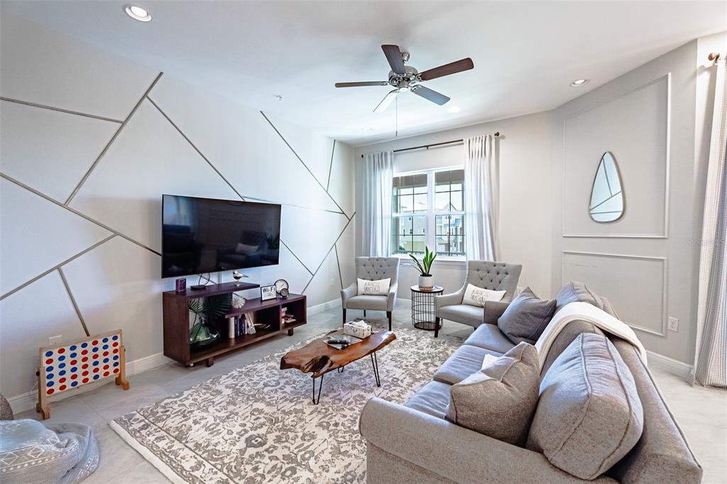 A living room features a geometric accent wall, a television, a sofa, and two chairs — 10345 LONGSHORE ROAD UNIT 31, PLACIDA, FL
