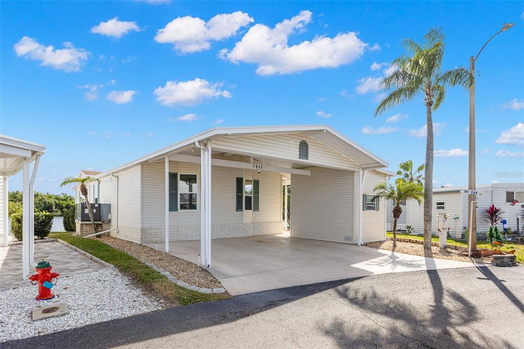 A single-story manufactured home with a white exterior, attached carport, and a red fire hydrant — 7013 MOUNT PINEY ROAD NE UNIT 724, ST PETERSBURG, FL