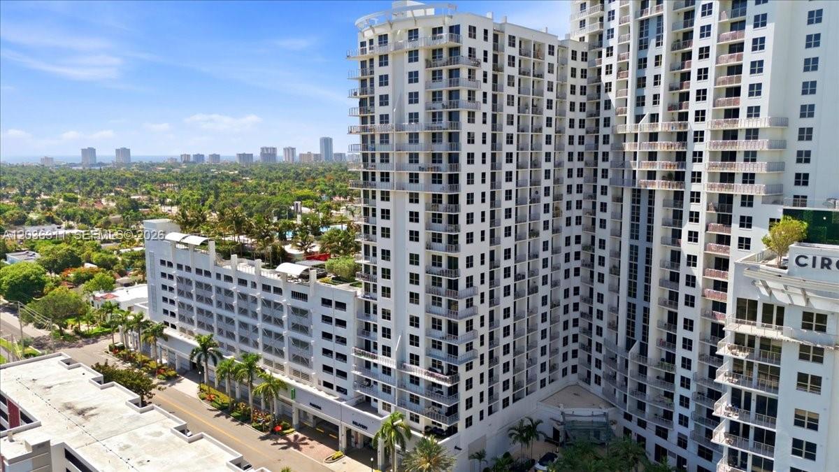 An aerial view shows a tall white residential high-rise building with balconies and an attached parking garage — 1776 Polk St # 703, Hollywood FL 33020, HOLLYWOOD, FL