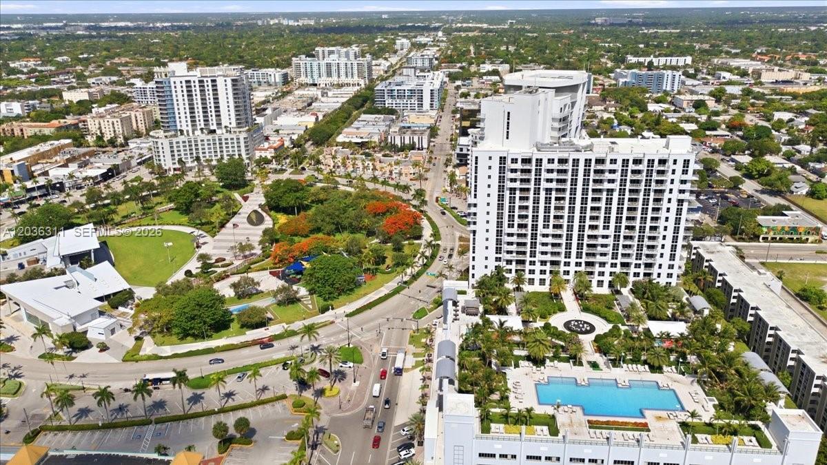 An aerial view shows a high-rise building, a swimming pool, and a park in a city — 1776 Polk St # 703, Hollywood FL 33020, HOLLYWOOD, FL