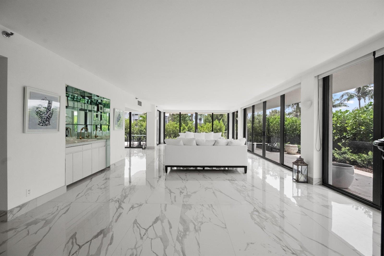 A bright living room features white marble floors, a wet bar, and large glass sliding doors — 2580 S Ocean Boulevard, Palm Beach FL 33480, PALM BEACH, FL