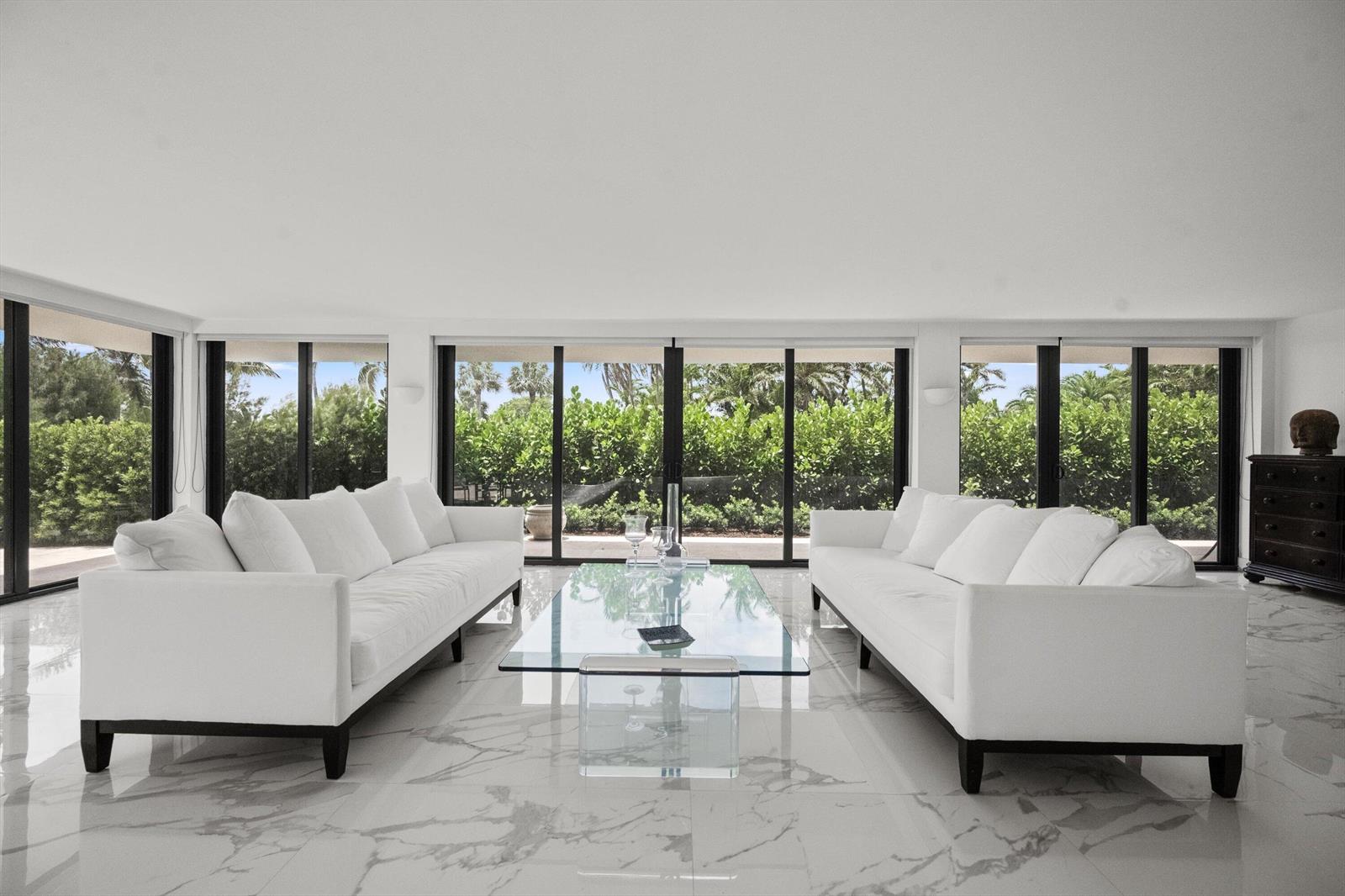A bright living room features two white sofas, a glass coffee table, and marble floors — 2580 S Ocean Boulevard, Palm Beach FL 33480, PALM BEACH, FL