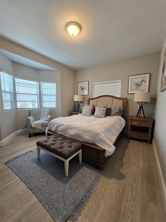 A bedroom features a bed with a tufted bench, a corner armchair, and light wood flooring — 244 LEXINGTON DRIVE, DAYTONA BEACH, FL