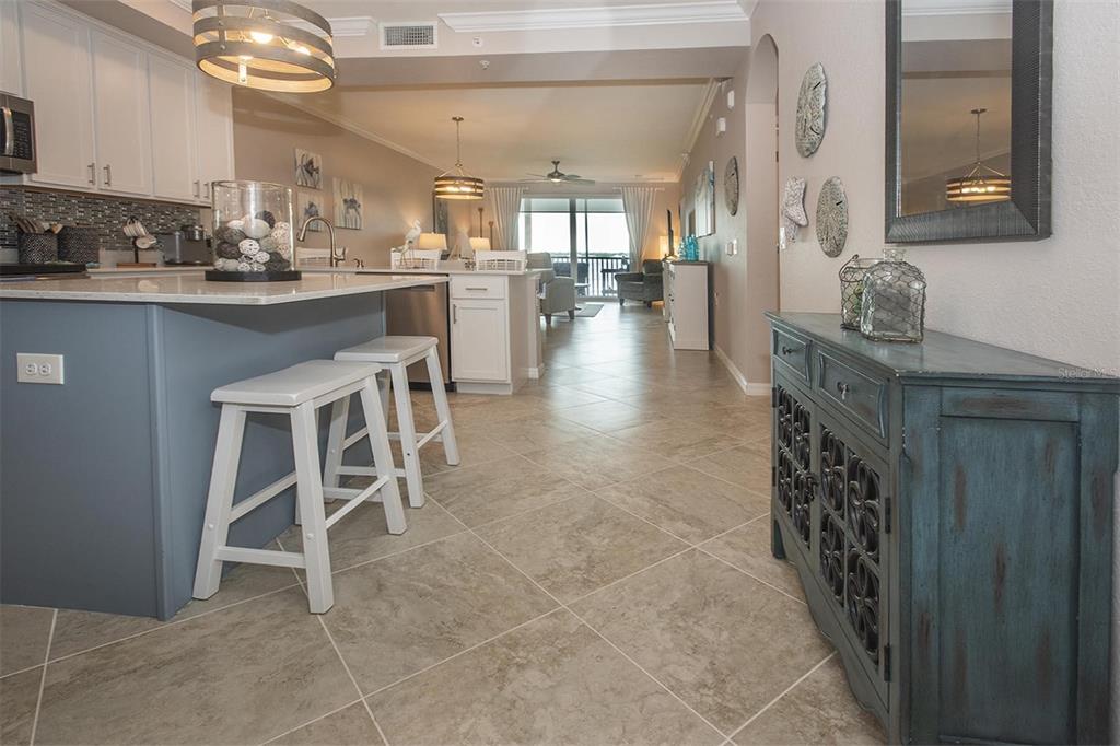 A kitchen with a blue island and white stools opens into a living area — 1010 TIDEWATER SHORES LOOP UNIT 204, BRADENTON, FL