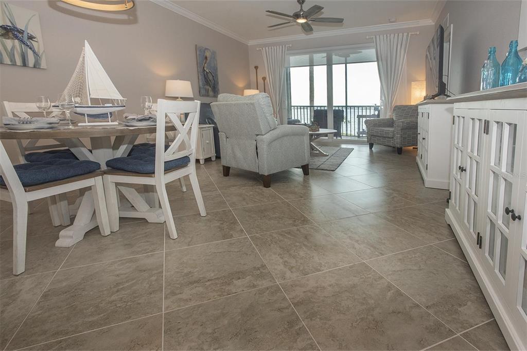 A dining area and living room with tile floors, a sailboat centerpiece, and balcony access — 1010 TIDEWATER SHORES LOOP UNIT 204, BRADENTON, FL
