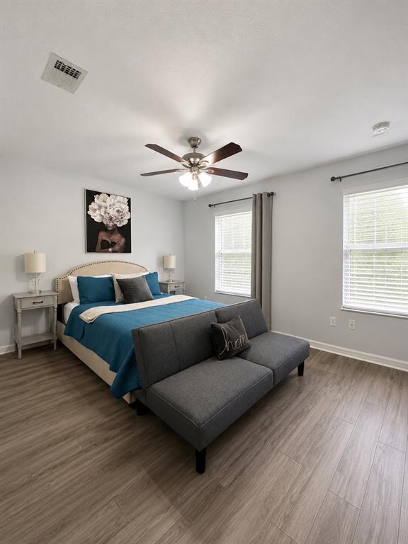 A bedroom features a bed with blue bedding, a gray sofa, and light wood flooring — 4663 SW 48TH DRIVE UNIT 137, GAINESVILLE, FL
