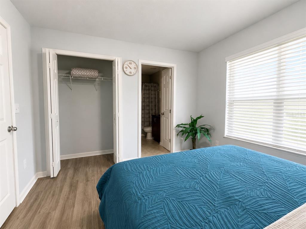 A bedroom features light gray walls, wood-look flooring, a closet, and an attached bathroom — 4663 SW 48TH DRIVE UNIT 137, GAINESVILLE, FL