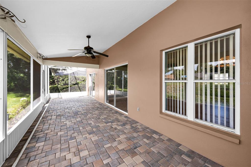 A covered patio with paver flooring, a ceiling fan, and large windows overlooking a yard — 8919 KEATS DRIVE, HUDSON, FL