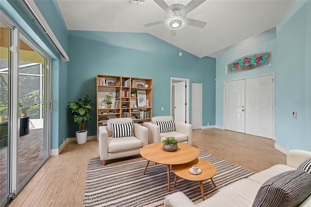 A living room with light blue walls, wood flooring, two armchairs, and a bookshelf — 8919 KEATS DRIVE, HUDSON, FL