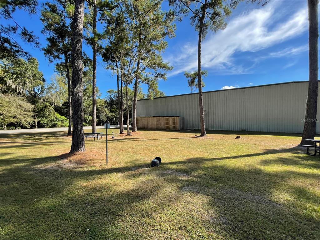 A grassy yard with pine trees and a picnic table beside a metal building — 3600 SW 47TH AVENUE, GAINESVILLE, FL