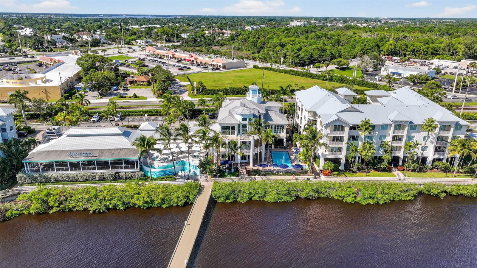 An aerial view shows a waterfront building complex with a pool, restaurant, and parking lot — 875 NW Flagler Avenue # 302, Stuart FL 34994, STUART, FL