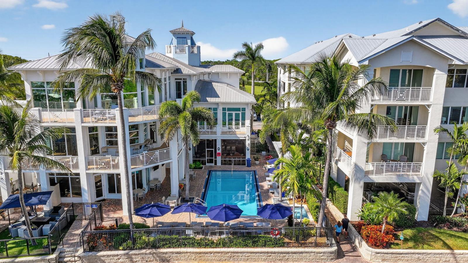 An aerial view of a swimming pool situated between two multi-story residential buildings with balconies — 875 NW Flagler Avenue # 302, Stuart FL 34994, STUART, FL