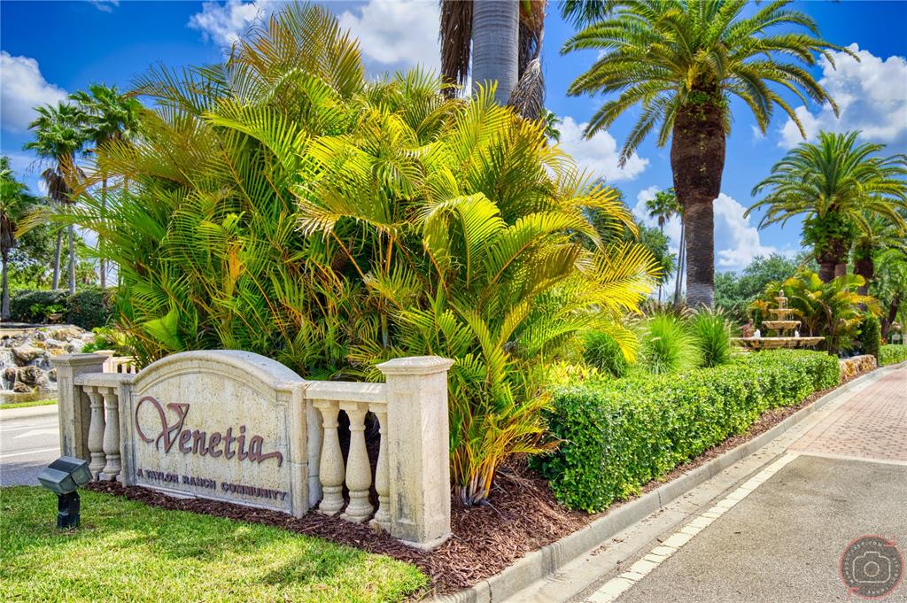 A stone sign for the Venetia community sits among palm trees and manicured landscaping — 4528 CANCELLO GRANDE AVENUE, VENICE, FL